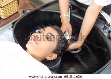 Hairdresser washing hair of serious young woman