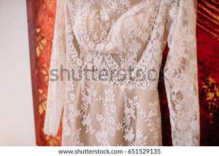 Short white dress hangs on red picture on the wall