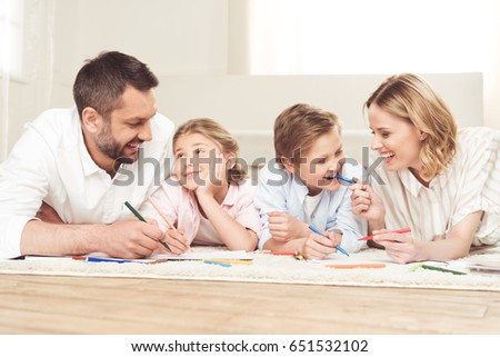 happy family drawing pictures while lying on the floor at home