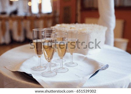 Champagne flutes stand on tray on white table