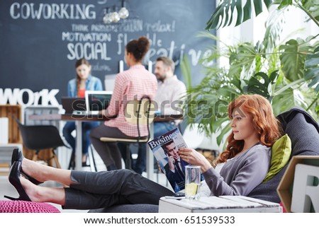 Woman taking business rest break reading newspaper in comfortable position Royalty-Free Stock Photo #651539533