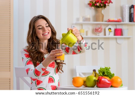 Young woman pouring juice into a glass from a juicer. Photo from the show where female blogger sharing some healthy eating tips.