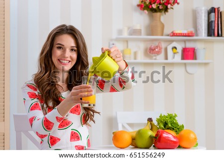 Woman pouring juice into a glass from a juicer. Photo from the show where female blogger sharing some healthy eating tips.