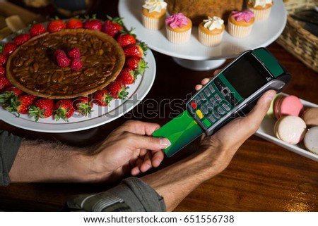 Customer making payment through credit card at counter in coffee shop