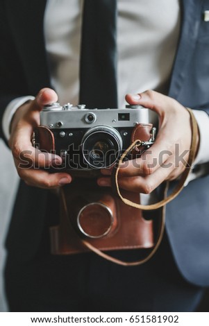 A young man in a jacket holds a retro camera