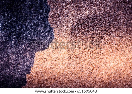 An abstract, high contrast background of a sea sand and rock shapes. Shallow depth of field, purple color tone.
