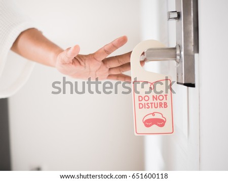 a person hand with do not disturb sign for private time moment of hotel and resort bedroom background