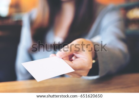 A beautiful Asian business woman holding and giving empty business card in modern loft cafe
