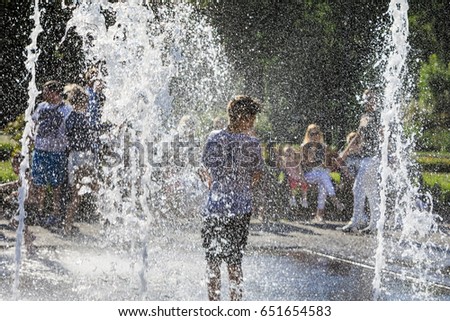 Happy children playing in a water fountain in a hot day