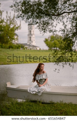 A girl is sitting in a boat near the lake