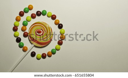 Lollipop and multi-colored dragee, isolated on the white background.

