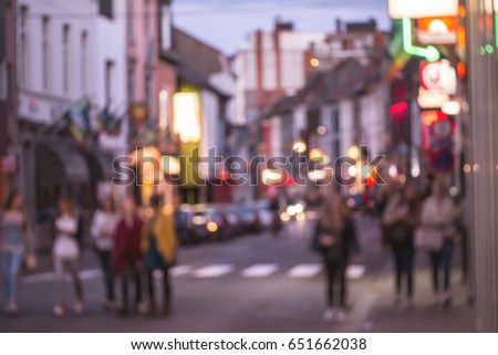 blurred colorful background from night walking street with people walking and shopping.