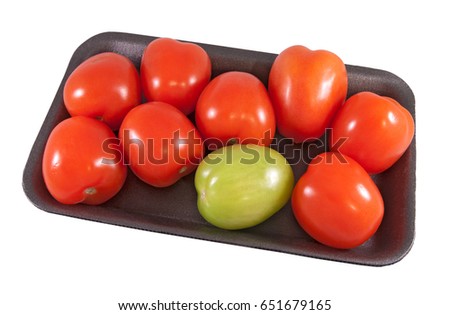 Eight red and one green tomatoes in the dark tray 