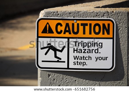Caution tripping hazard sign on a wall.