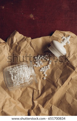 glass jar with beads. set for creativity on the background of red, wooden walls. on the crumpled paper