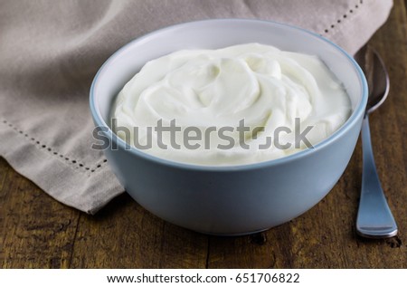 Natural yoghurt in bowl on wooden table background with napkin - Creamy natural Greek yogurt swirled in bowl with spoon Royalty-Free Stock Photo #651706822