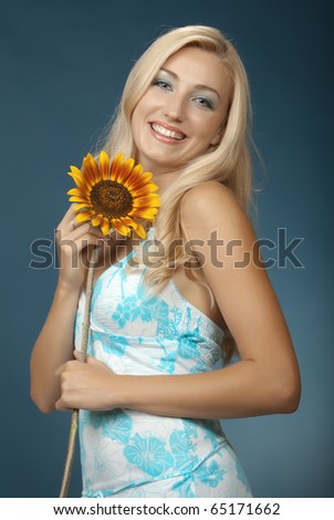 The beautiful girl with white hair on a dark blue background. She has control over a sunflower