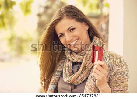Cheerful excited young woman with credit card standing outdoors on a sunny day  Royalty-Free Stock Photo #651737881