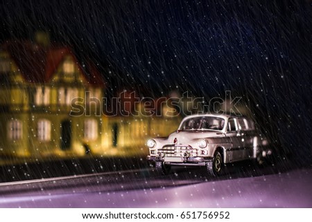 Photo of a miniature GAZ-12 ZIM car. Retro car rides through the city on a winter night. Snowing. Children's toy. Creative, realistic picture.