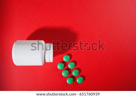 Medical pills on a colored background with a white vial