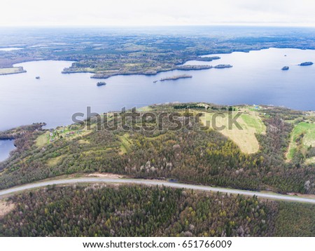 Beautiful view from a road going through the beautiful lake and forest, surrounded with water on both sides, shot above from drone, aerial vibrant picture