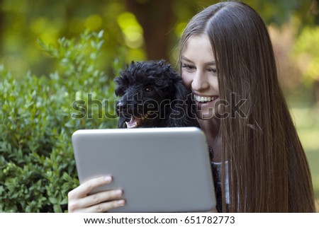 The young beautiful smiling  woman holds her dog and together  looking at tablet