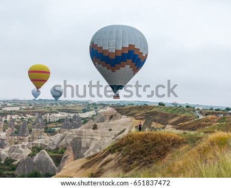 Hot air balloons (atmosphere ballons) flying over mountain landscape at Cappadocia, UNESCO World Heritage Site since 1985 - Turkey