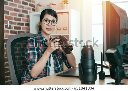 happy pretty photographer woman right review picture and choosing photo sitting in editing office working desk with face to camera smiling.