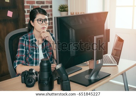 pretty calm female photographer woman working at office desk and editing business photo thinking selection best for online stock company.