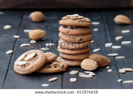 Chocolate chip cookies with almond petals. Homemade baked cookies on the black wooden background.