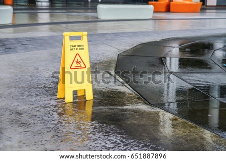 old caution wet floor warning sign near wet area with blurred background