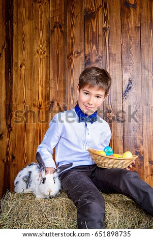 Easter holidays. Happy child boy sitting on a haystack with Easter Bunny.