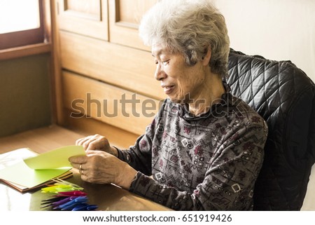 Japanese senior lady folding paper cranes at home