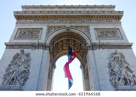 Arc de Triomphe with french flag waving on sunny day