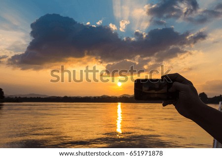 woman hand holding smartphone at sunset.
