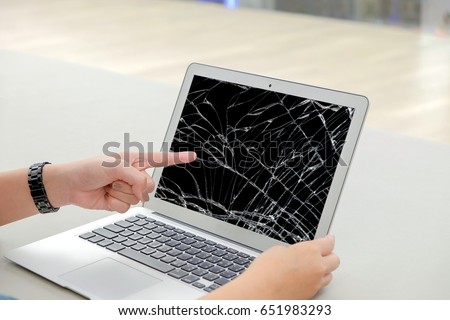 Left finger of woman, she pointing at the screen laptop, the screen cracked and damaged.