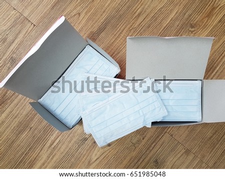 
Medical surgical face mask inside boxes on wooden background. View from above