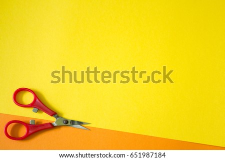 red scissors on orange and yellow background
