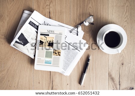 Newspaper with tablet on wooden table Royalty-Free Stock Photo #652051432