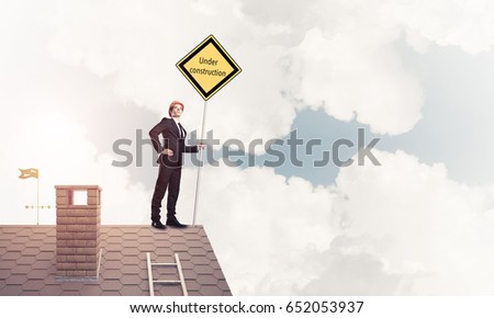 Man holding safety sign indicating under construction notice. Mixed media