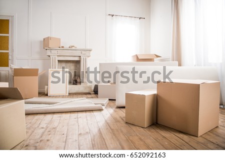 Picture frame and cardboard boxes in empty room, relocation concept