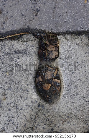 Boot footprint on cracked concrete floor.