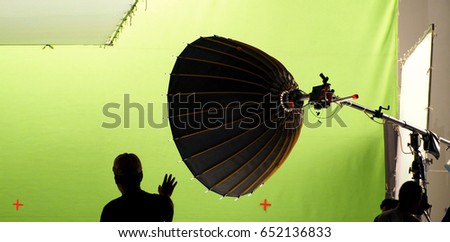 Big studio light equipments and man setting for shooting movie video or photo film and green screen background.