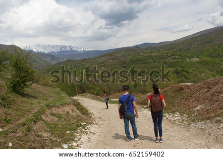 Travelers travel on the road in mountains go trekking Countryside, village - mountains, Clouds. Active hikers