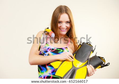 Attractive slim woman wearing swimsuit with mask tuba, flippers, snorkel having fun studio shot on grey. Young female dreaming about summer vacation. Snorkeling swimming concept