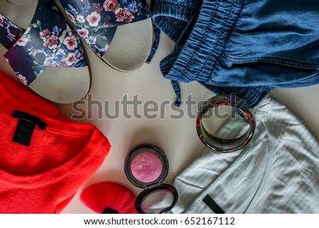 Spring-summer set, ladies' clothing, jeans, sandals floral motifs, t-shirt, bracelets, blush and make-up brush. Copy space. Concept fashion and makeup.