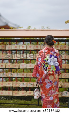 Japanese woman in Kimono reading O-mikuji (fortune prediction)  strips of paper at shinto shrines and buddhist temple in Japan. Fold up the paper attach to a pine tree or a metal wires for bad fortune