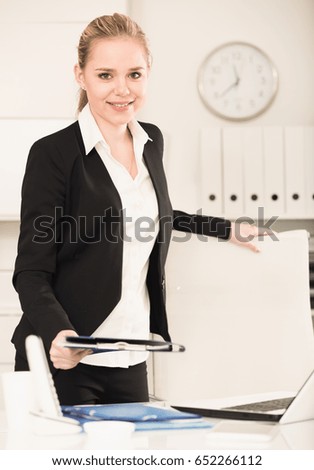 Portrait of stylish young business woman standing in office holding clipboard