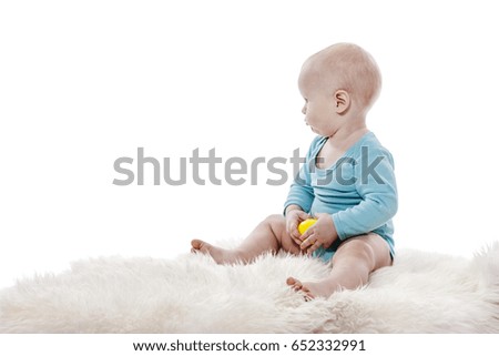 Baby boy sitting on white fur carpet isolated on white