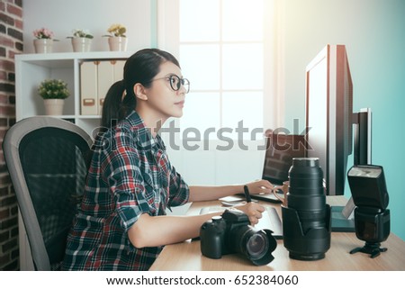smiling young picture company office worker girl using digital pad editing and holding technology pen looking at computer retouch business photo.